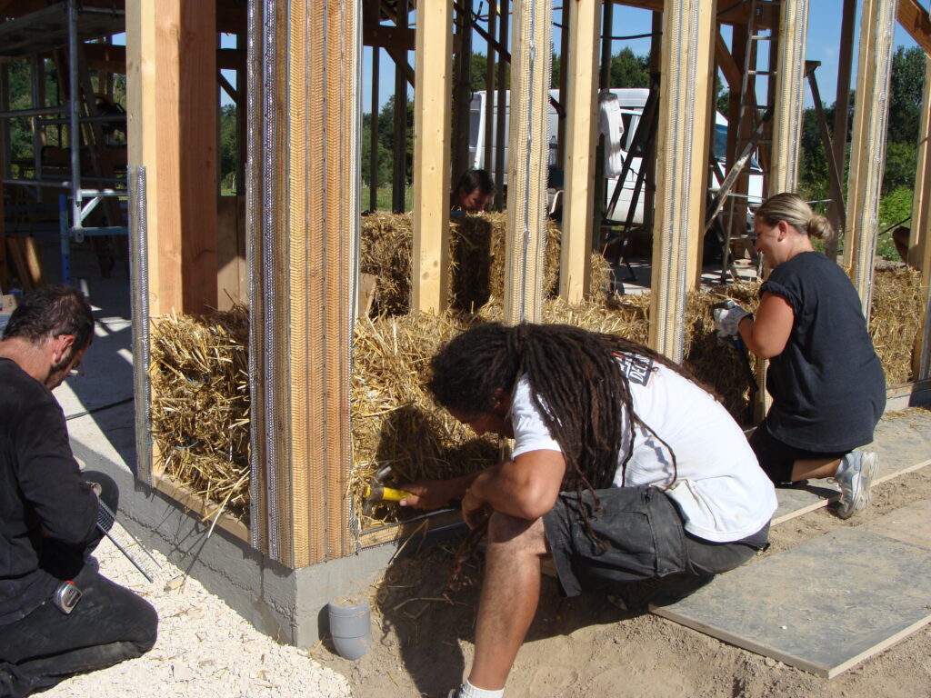Construction d'une maison en bois et paille. Mise en place de la paille en phase chantier.